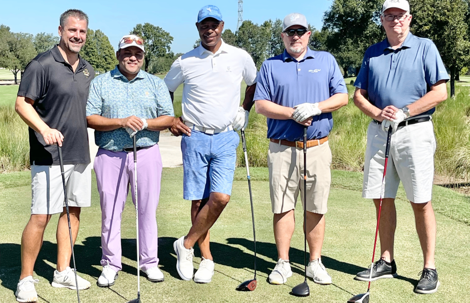 Five golfers standing together on the tee box before a round.