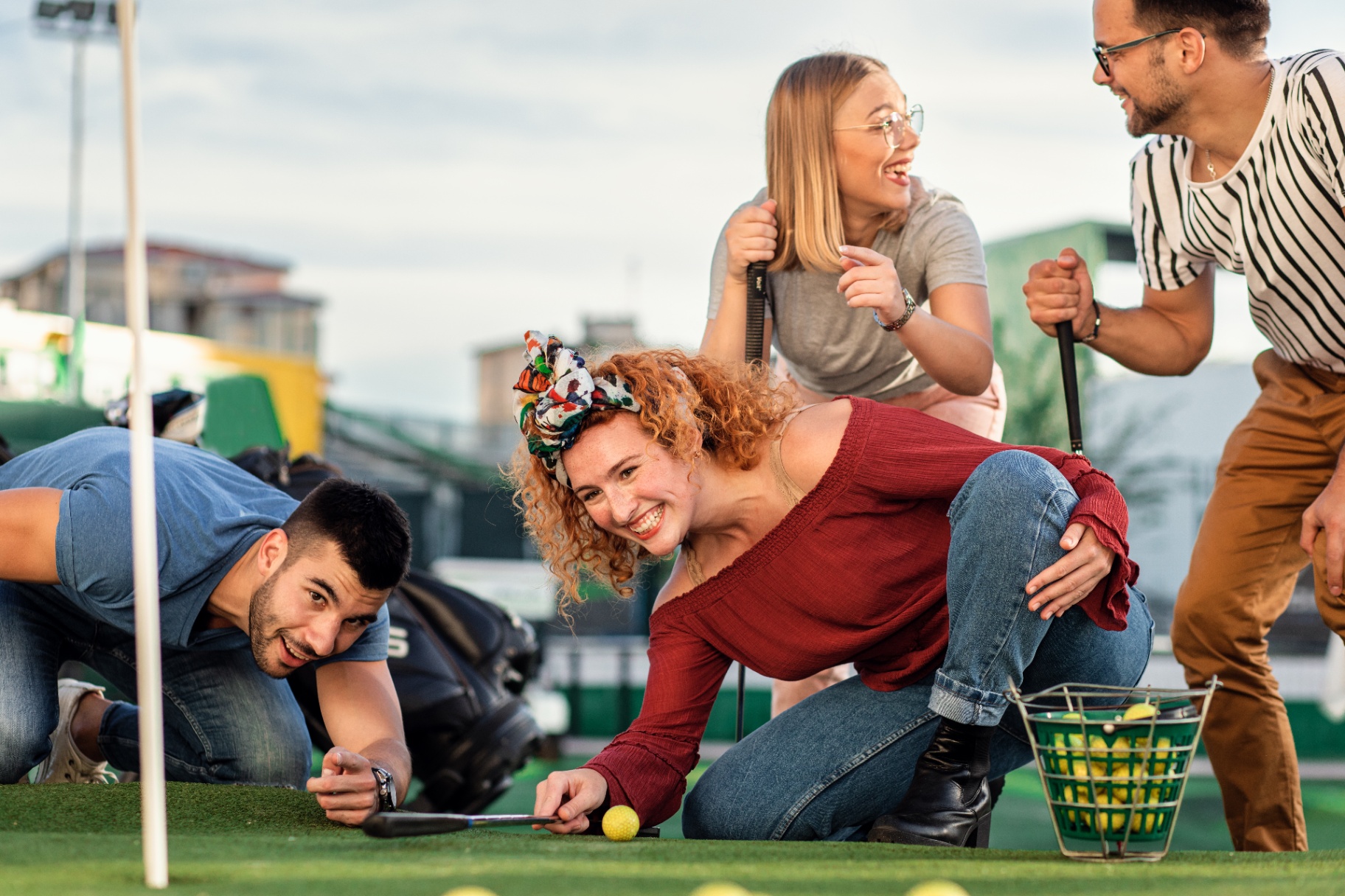 Friends laughing together while playing mini golf in the city.